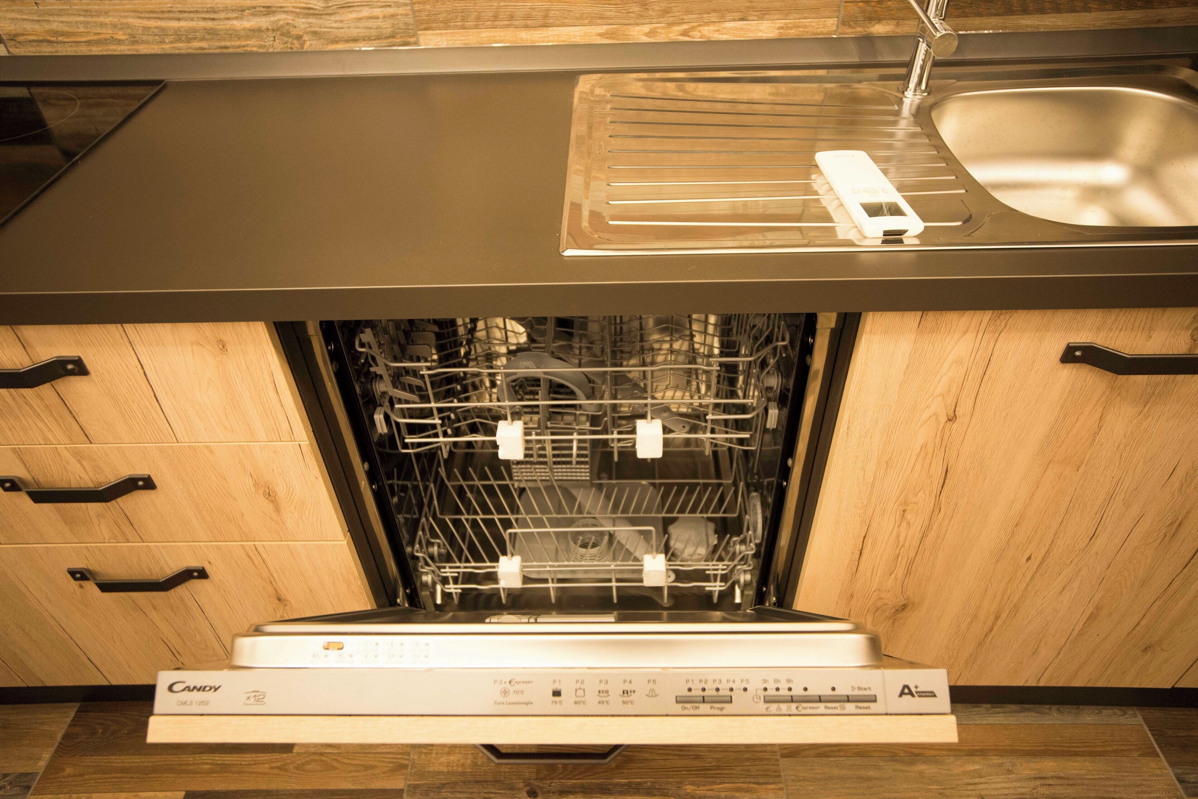 Una cocina moderna con lavavajillas, armarios de madera y un lavamanos de acero inoxidable.
