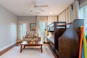 Un dormitorio con literas, ventilador de techo, sofá y mesa de centro.