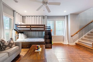 Une chambre avec un lit superposé, un canapé, une table basse et un escalier.