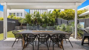 An outdoor patio with a rectangular table and six chairs, surrounded by a glass enclosure. - The Palms on Nautilus (Kingscliff)