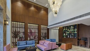 A spacious lobby with a high ceiling, a large chandelier, and a variety of seating options including sofas and armchairs. - Regenta Place Ahmedabad (Ahmedabad)