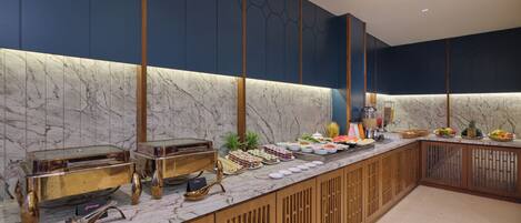 A buffet setup with various food items and a marble countertop.