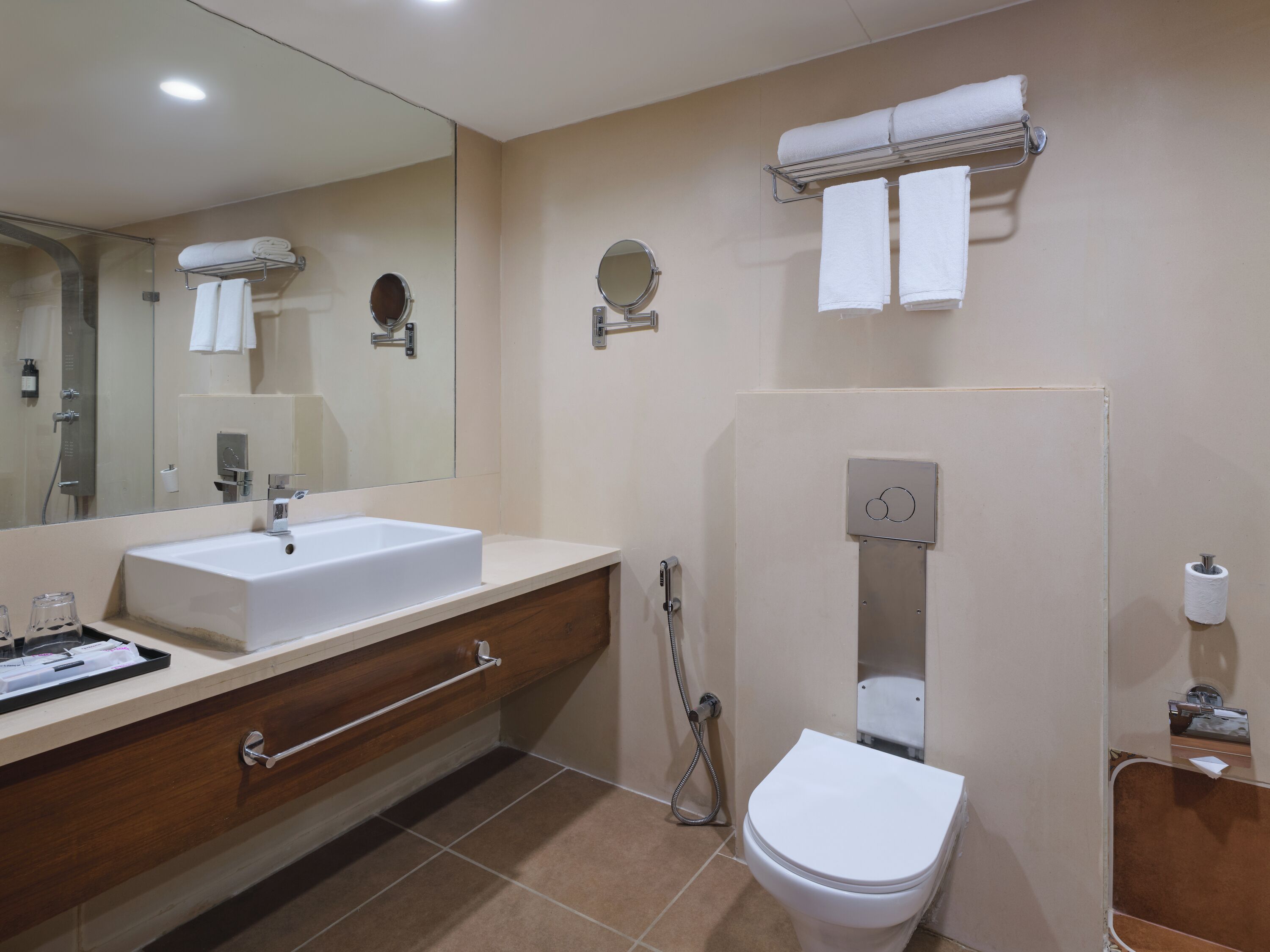 A modern bathroom with a sink, mirror, towel rack, toilet, and shower.