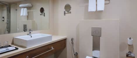 A modern bathroom with a sink, mirror, towel rack, toilet, and shower.