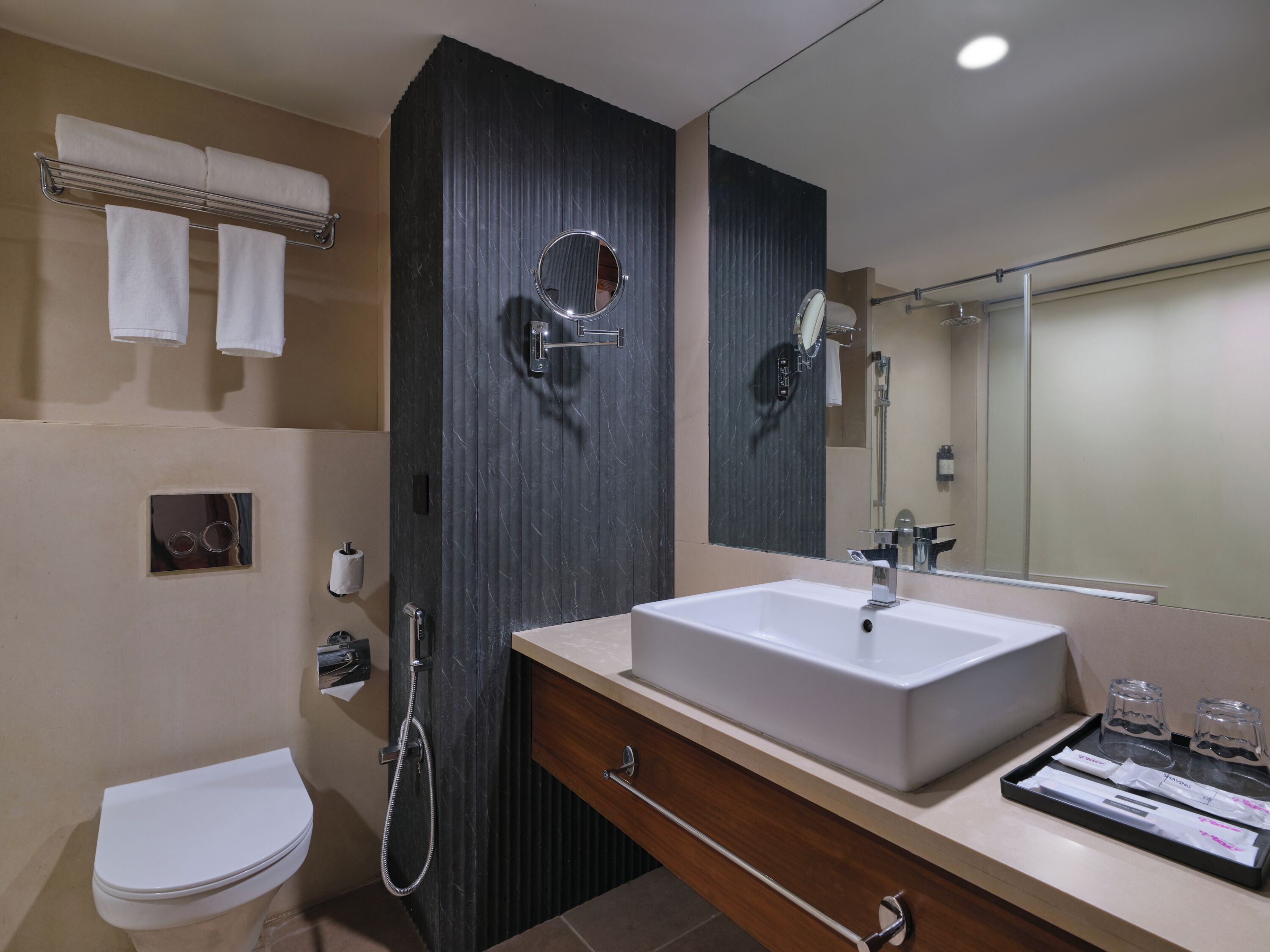 A modern bathroom with a large mirror, a sink, and a toilet.