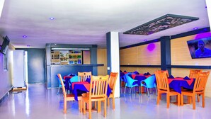 A restaurant with wooden tables and chairs, a bar area, and a television screen on the wall. - KER HOTEL DODOMA (Dodoma)