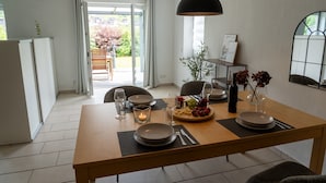 A dining area with a table set for two, a candle, and a fruit platter.
