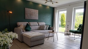 A modern living room with a grey sofa, a small round table, and a green armchair.