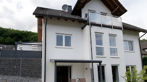 A two-story house with a patio, a dining area, and a small garden.
