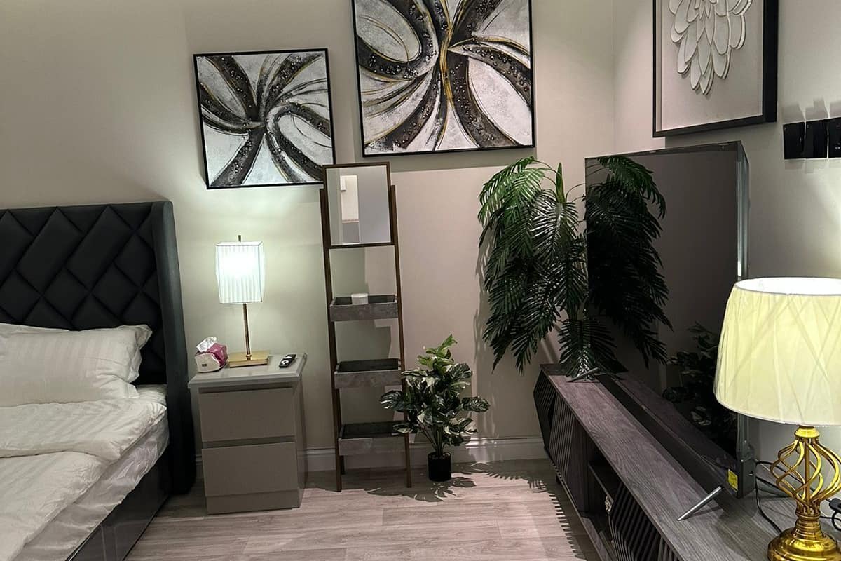 A modern bedroom with a bed, bedside tables, a mirror, a dresser, and decorative wall art.