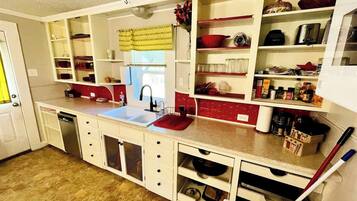 A compact kitchen with white cabinetry, a red countertop, and a built-in dishwasher.