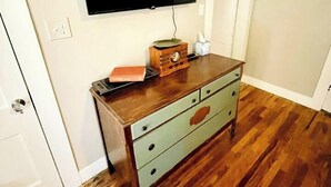 Une pièce comprenant une commode en bois, un téléviseur à écran plat fixé au mur et une porte donnant sur une autre pièce.