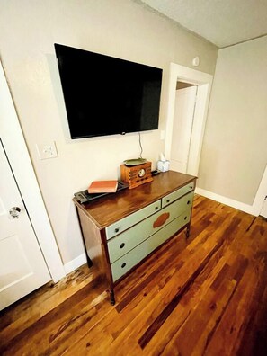 Ein Zimmer mit einem Holzkapuzenbord, einem flachbildfernseher an der Wand und einer Tür zu einem weiteren Raum.