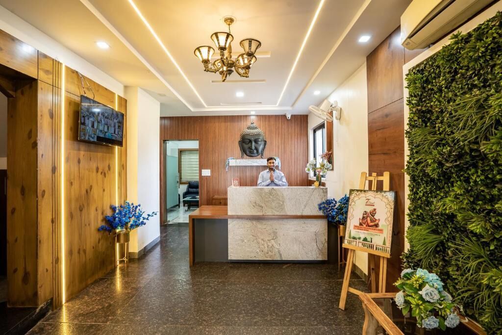 A reception area with a marble counter, a Buddha statue, and a wall with greenery.