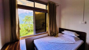 A room with a bed, a window with curtains, and a view of greenery outside. - Ventara Clouds Resort (Darjeeling)