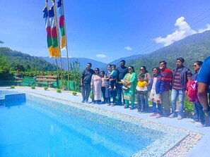 A group of people standing by a pool with a mountainous backdrop. - Ventara Clouds Resort (Darjeeling)