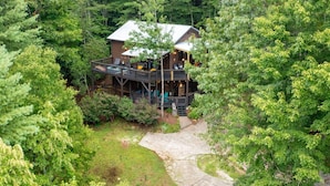 Une cabane dotée d’une terrasse et d’un espace extérieur aménagé, le tout entouré d’une forêt dense.