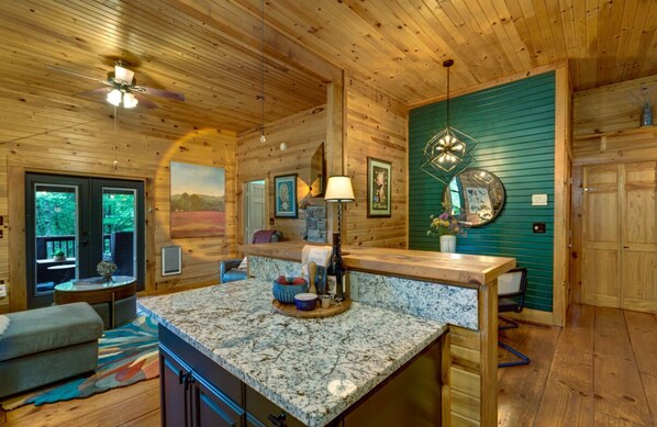 Interior acogedor de una cabaña con una zona de cocina que incluye encimera de granito, armarios de madera y una mesa de comedor.