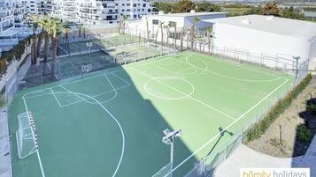 Een meerlaags woongebouw met een basketbalveld.