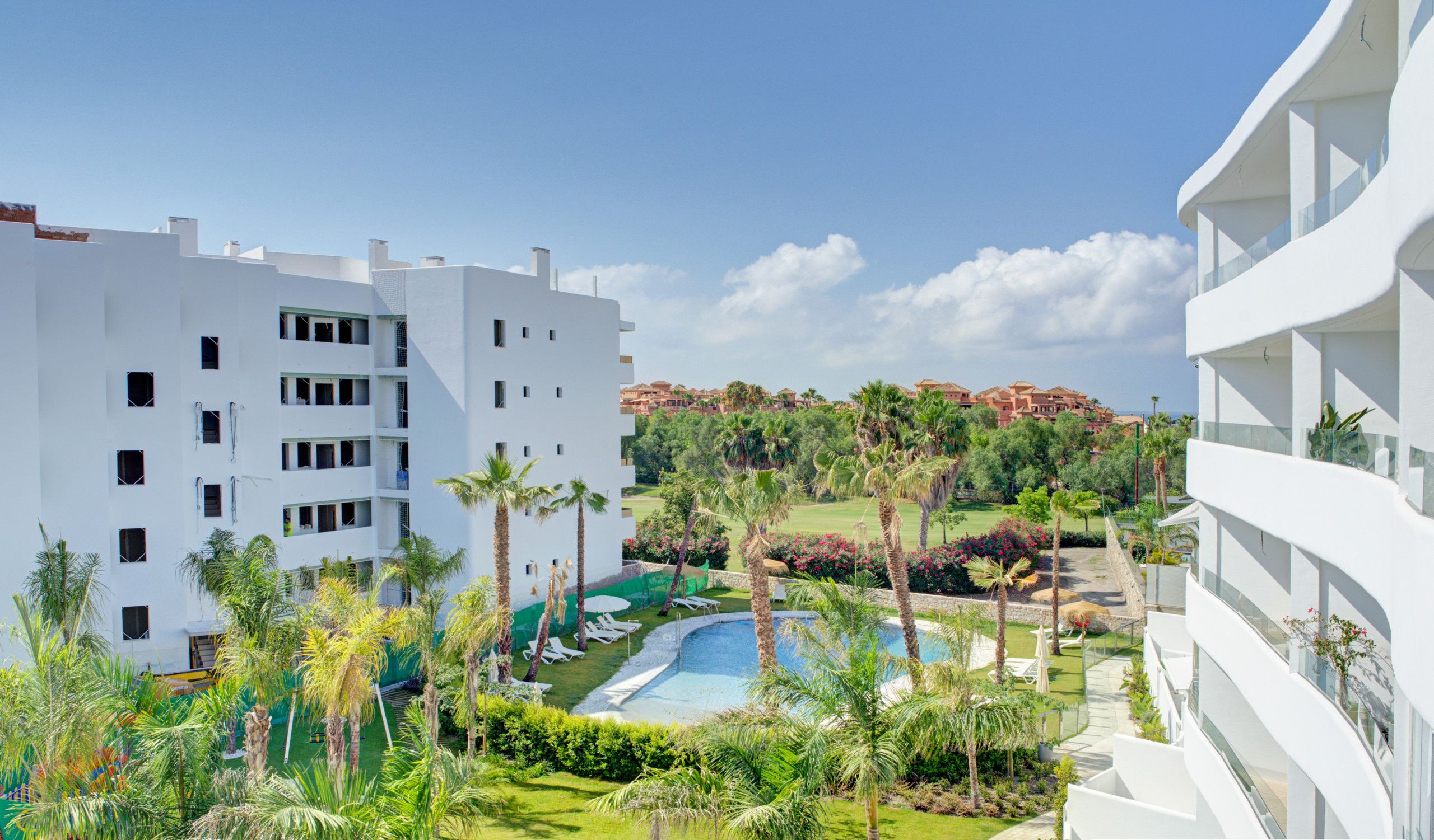 Et moderne hotel med pool, frodigt grønt og frit udsyn til det omkringliggende landskab.