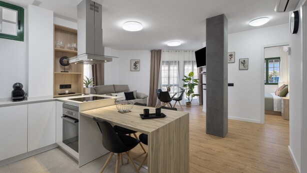 Eine moderne Küche mit Kochinsel, integriertem Backofen und Essbereich mit Stühlen und Tisch.