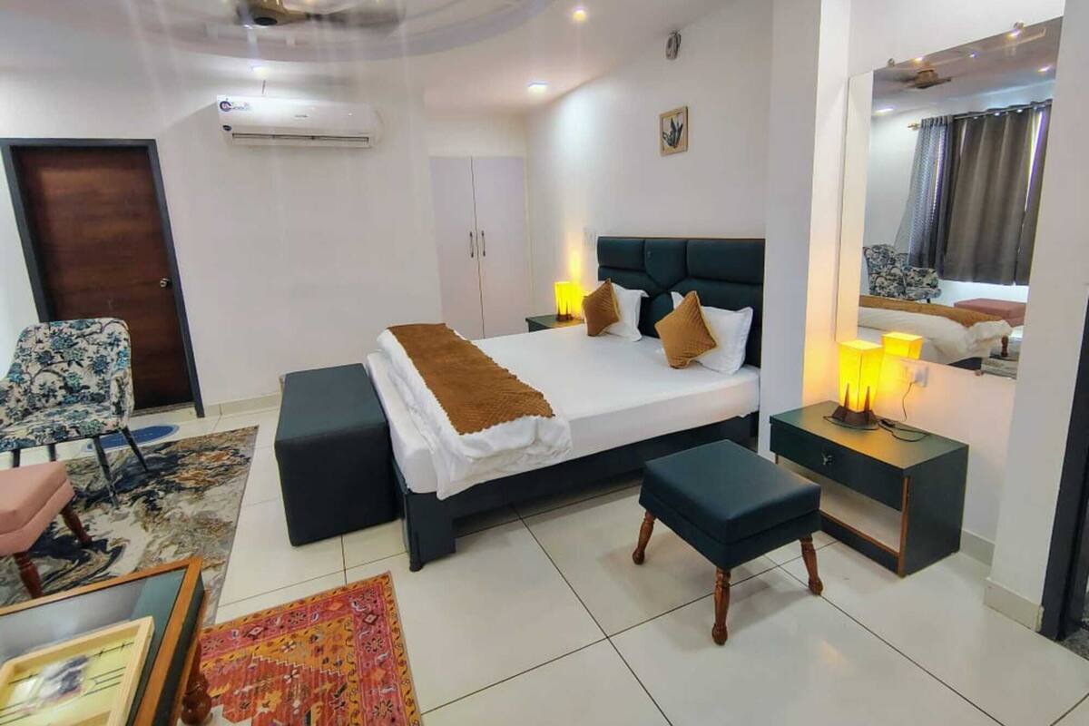 A modern bedroom with a large bed, bedside tables, a chair, and a mirror.