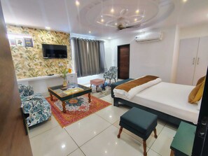 Una habitación luminosa con una cama, un sofá, una mesa de centro y un televisor.