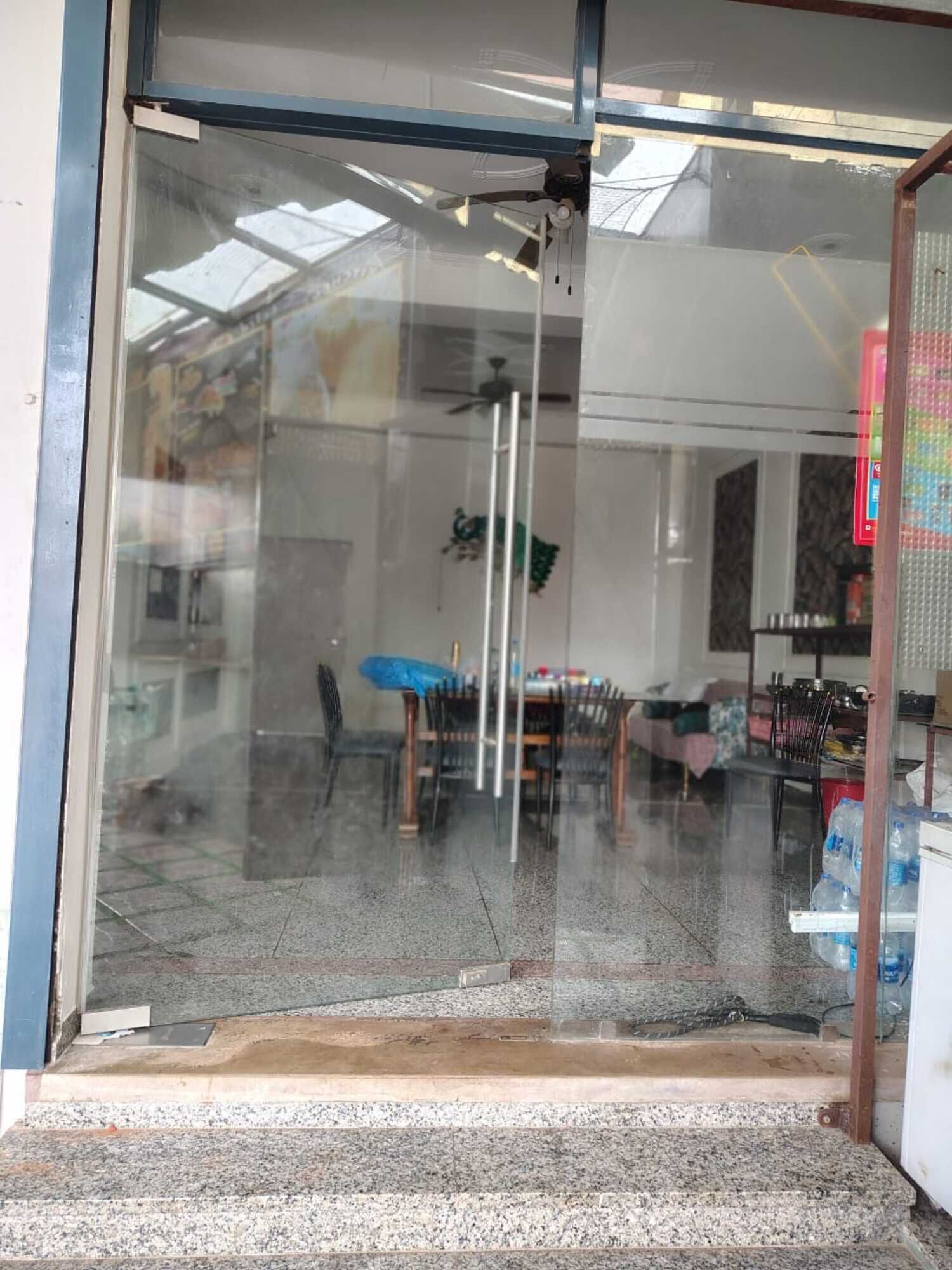 Puerta de vidrio que da acceso a un espacio con comedor visible en su interior.