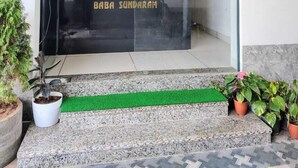 A reception area with a glass door, a reception desk, and a sign that reads "RECEPTION". - Baba Sundaram Hotel & Restaurant (Shri Madhopur)