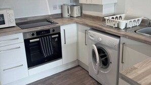 A compact kitchen with a built-in oven, a microwave, a toaster, and a washing machine.