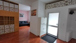 A room with a wooden floor, a black sofa, a white cabinet, and a door leading to another room. - Quiet vacation apartment near Cologne: Hürth, centrally located (Hürth)