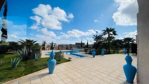 A courtyard with a swimming pool, palm trees, and blue vases. - Villa Dar Yobedi in Essaouira, swimming pool, hammam, ideal for families & groups (Essaouira)