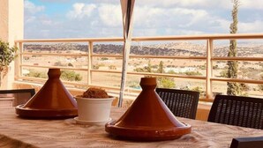 A terrace with a table set for dining, overlooking a desert landscape. - Villa Dar Yobedi in Essaouira, swimming pool, hammam, ideal for families & groups (Essaouira)