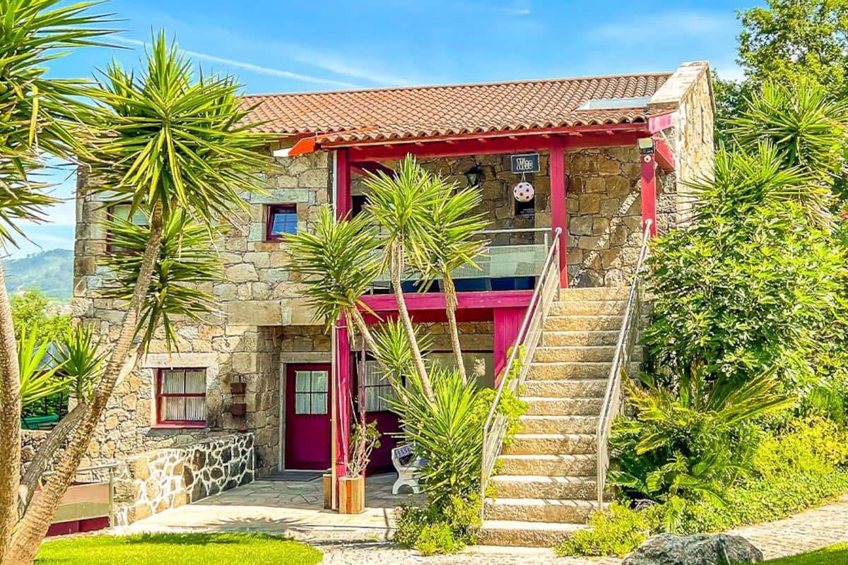 A stone building with a red roof, a staircase, and a small porch area.