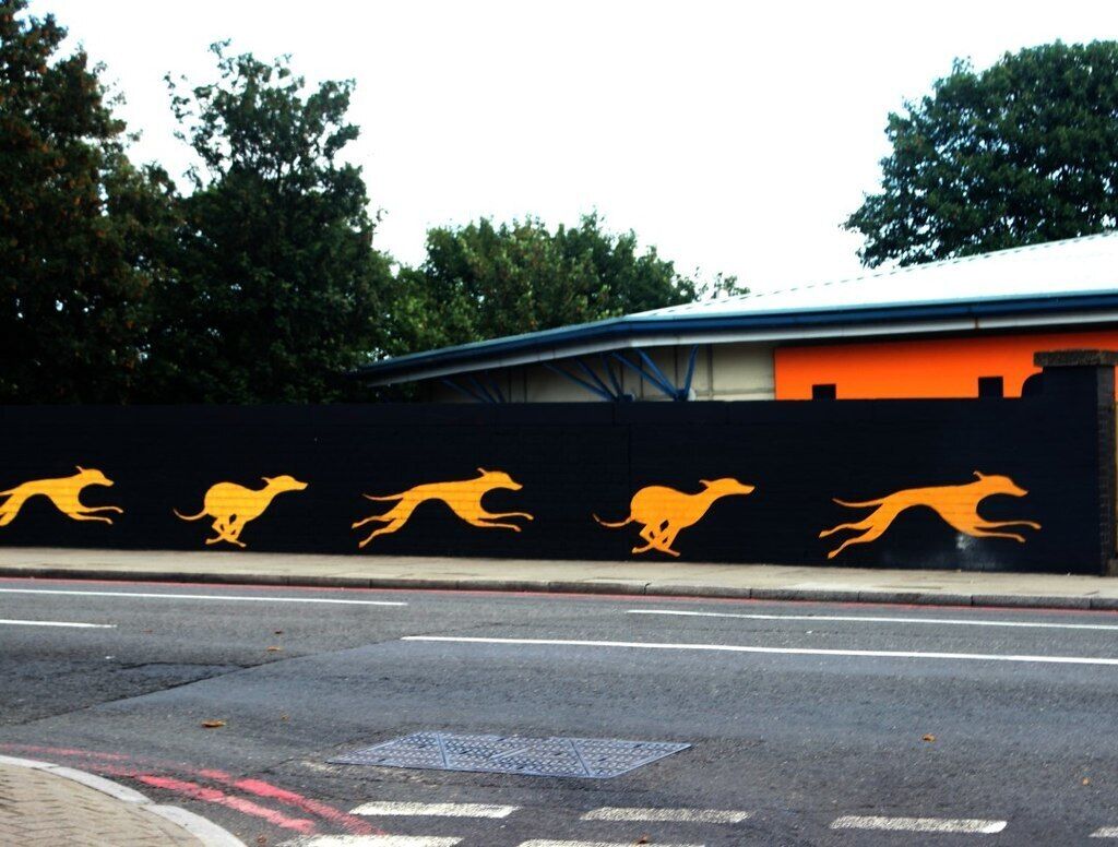 A wall with kangaroo silhouettes and a building with a curved roof.