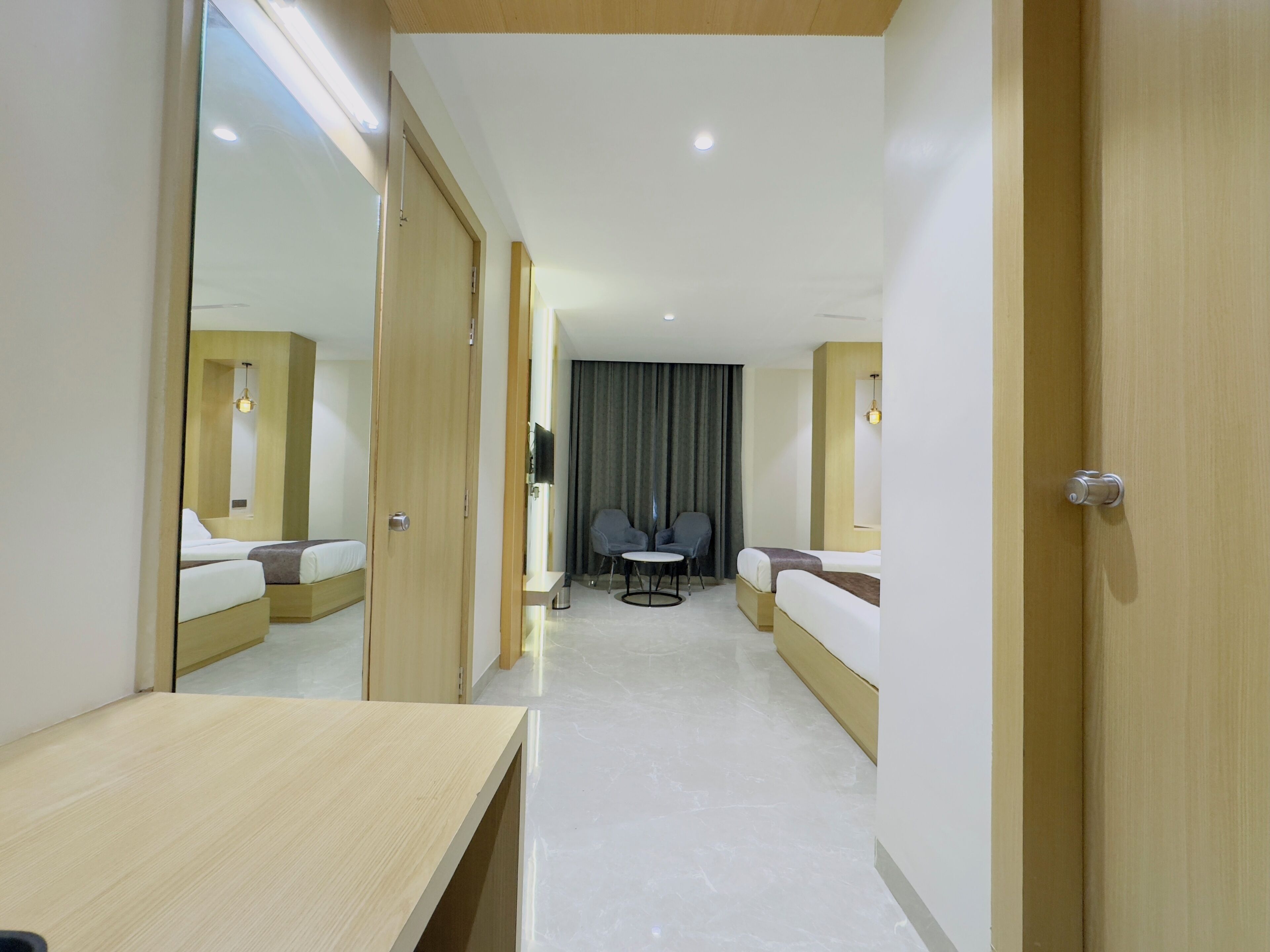 A hotel room with a bed, a desk, a chair, a TV, and a mirror.