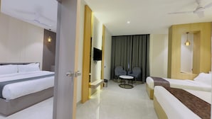 Habitación de hotel con dos camas, televisión, una mesita y ventilador de techo.
