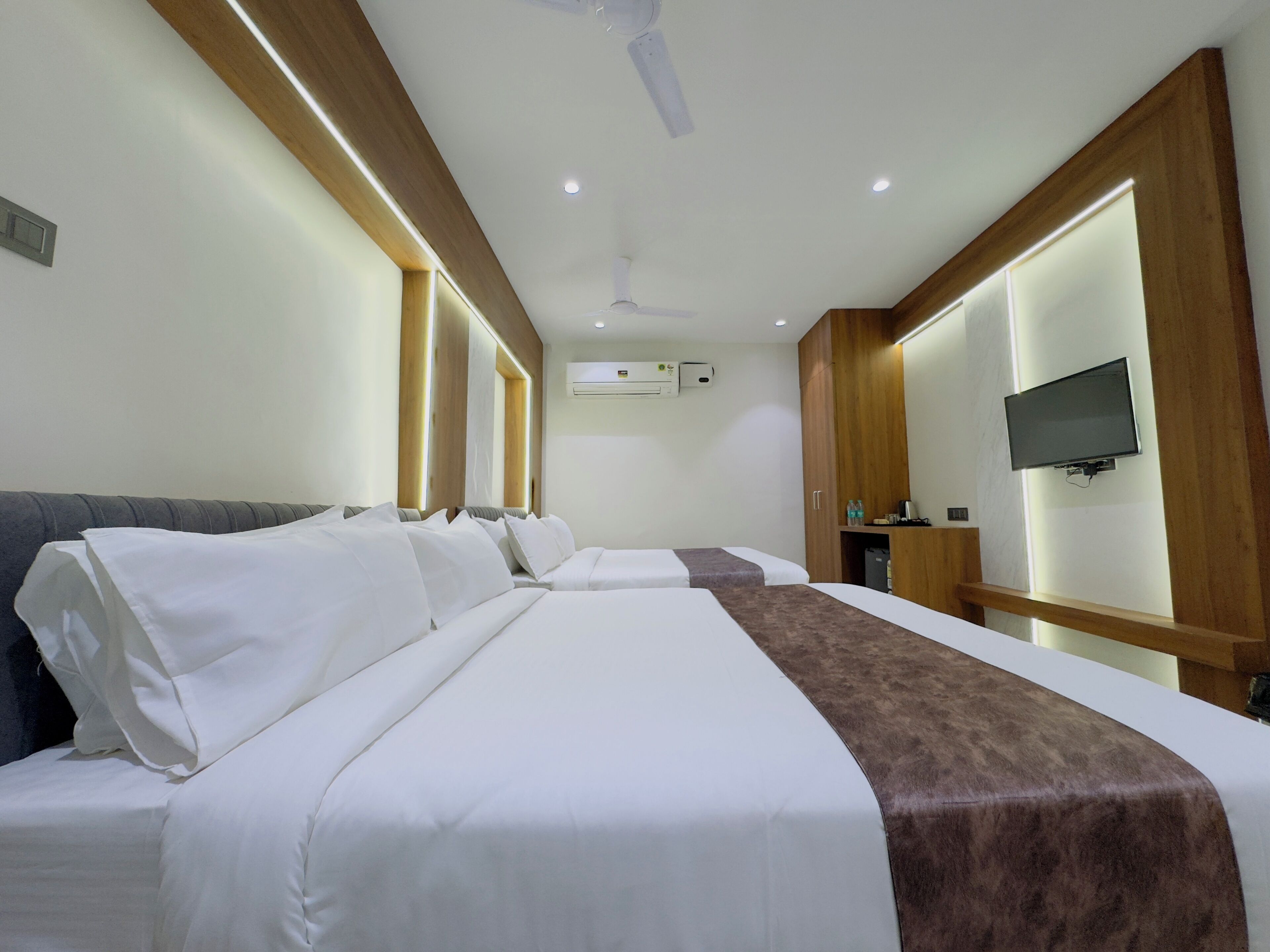 Une chambre d’hôtel avec deux lits, une télévision et un ventilateur de plafond.