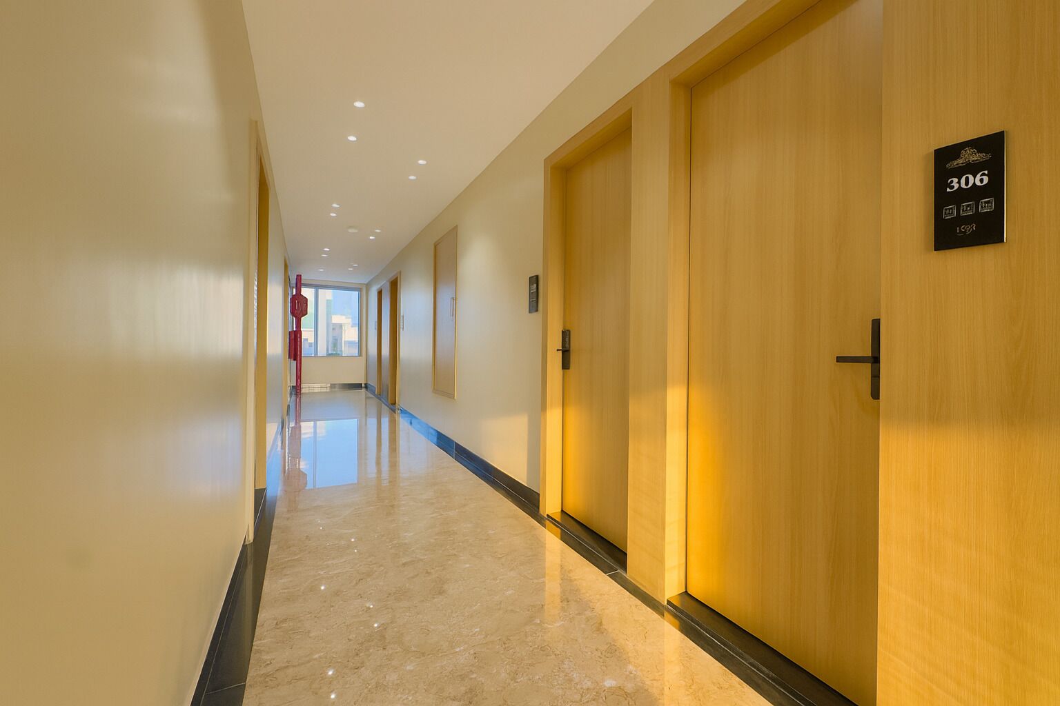 Un pasillo de hotel con puertas de madera, un letrero con número y suelo pulido.