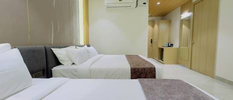 A hotel room with two beds, a wardrobe, an air conditioning unit, and a mirror.
