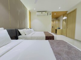 A hotel room with two beds, a wardrobe, an air conditioning unit, and a mirror.