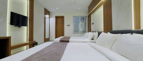 A hotel room with two beds, a TV, a large window, and wooden paneling.