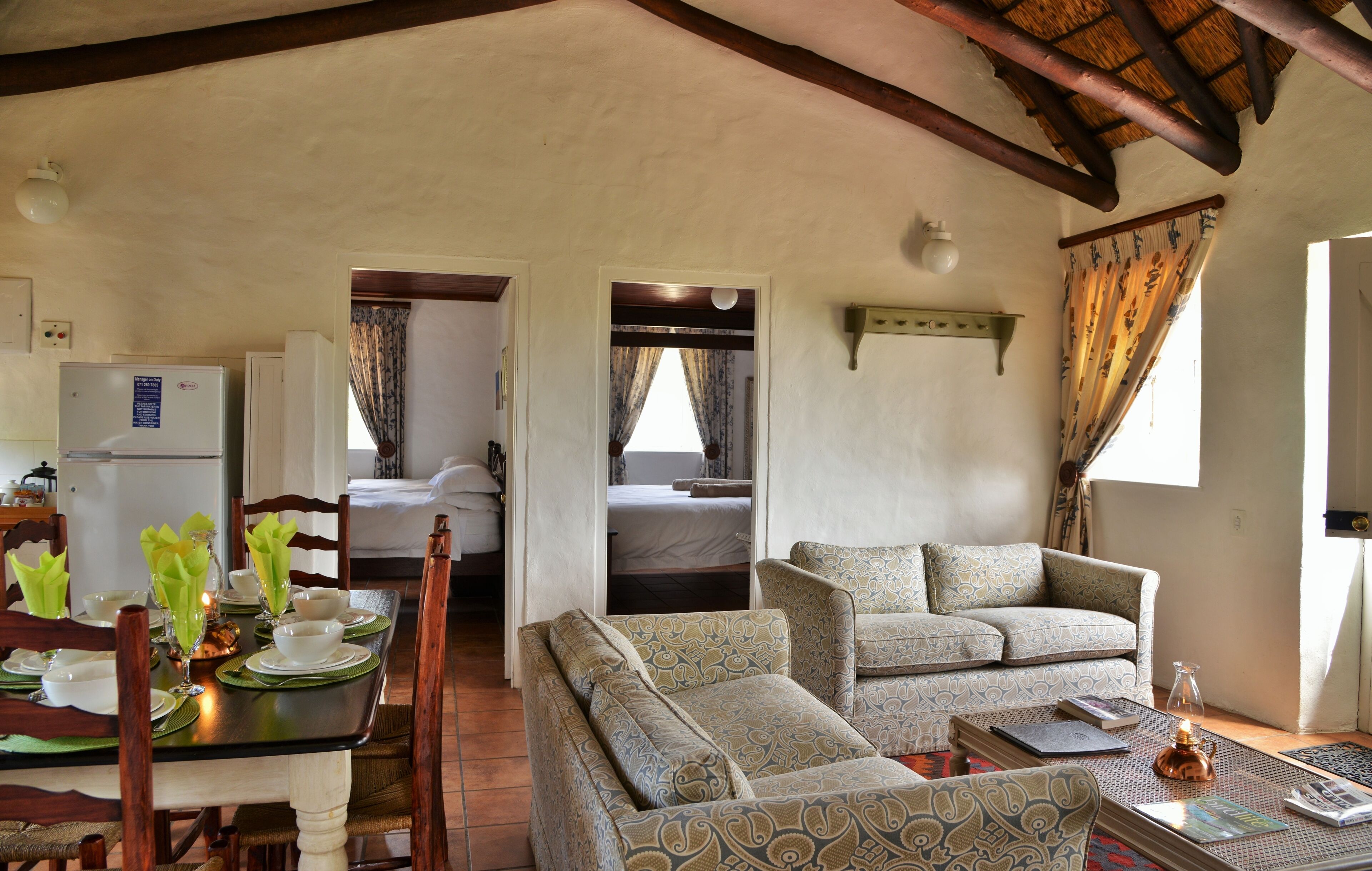 A cozy living area with a dining table set for two, a sofa, and a bed in the background.