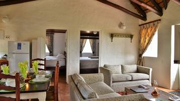 A cozy living area with a dining table set for two, a sofa, and a bed in the background.