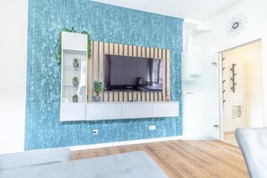 Un salon moderne avec un téléviseur fixé au mur, un mur recouvert de panneaux en bois et une étagère intégrée agrémentée de plantes.