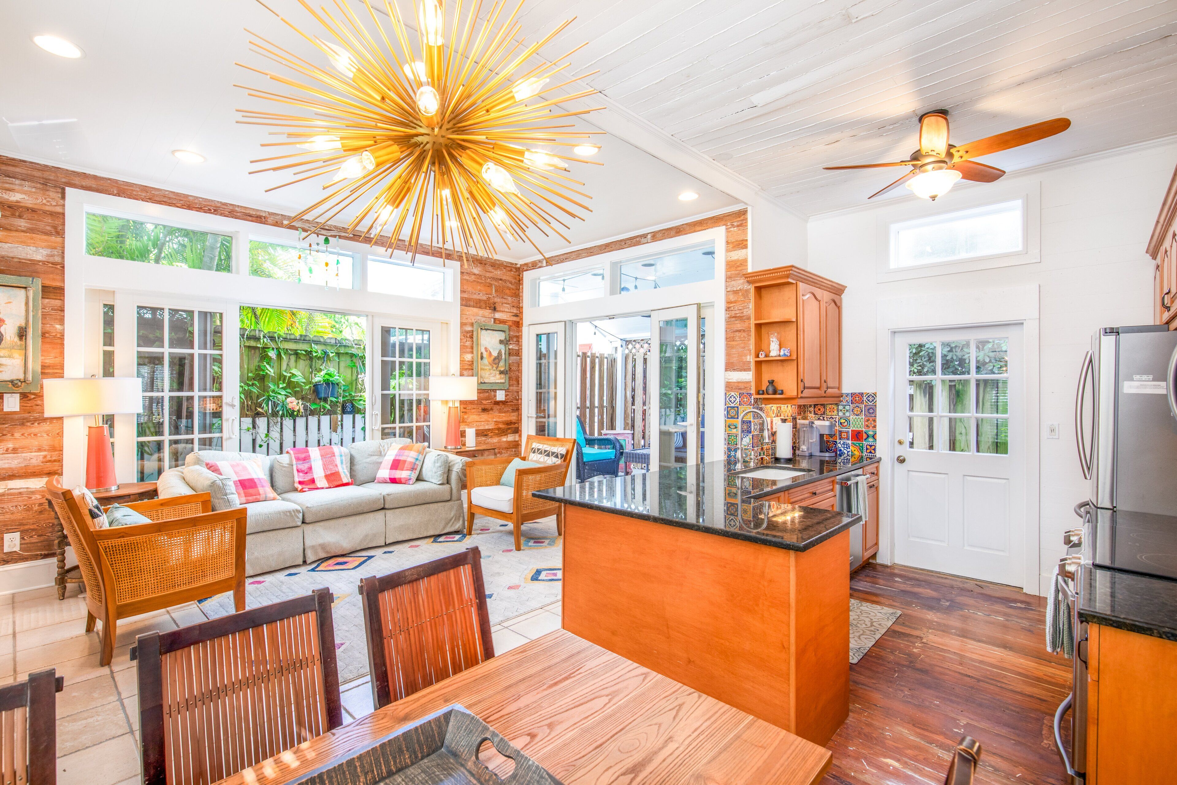 Uma sala de estar espaçosa com um sofá grande, mesa de jantar de madeira e cozinha com ilha central.