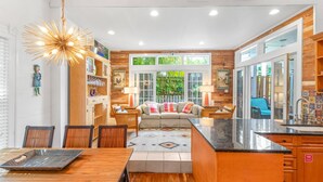 Una cocina moderna con comedor, armarios de madera y un amplio ventanal con vistas a un jardín.