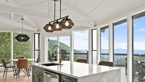 A modern kitchen with a large island, stainless steel appliances, and a view of a deck and mountains. - Luxury Mountain Home in Banner Elk with unobstructed views & Infrared Sauna! (Seven Devils)
