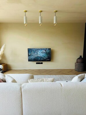 A modern living room with a flat-screen TV mounted on the wall, a sofa set, and a decorative vase. - Luxurious House in the Flemish Ardennes Near Ghent (Gavere)