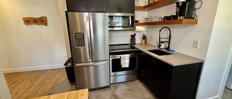 Una cocina moderna con electrodomésticos de acero inoxidable, una mesa de madera y un horno empotrado.